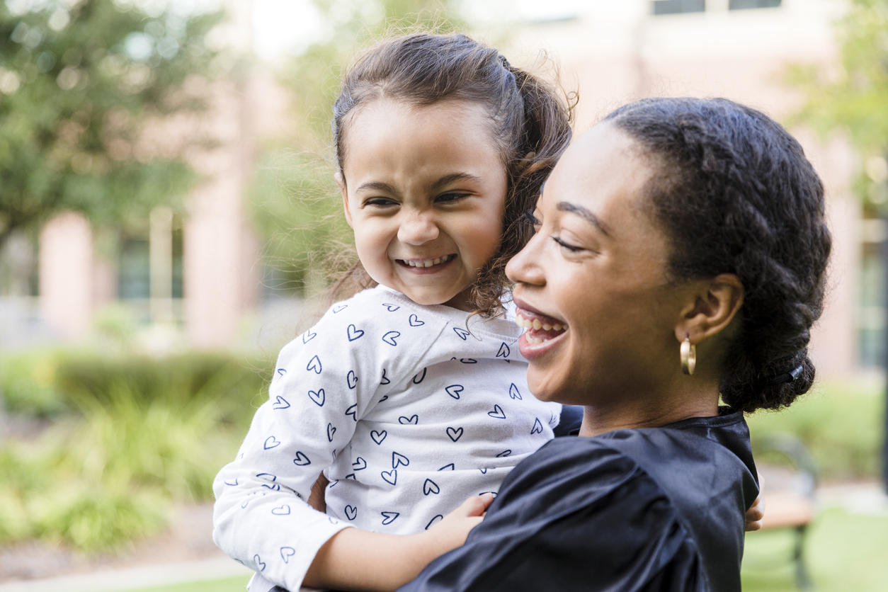 Young girl and graduate mom both smile happily