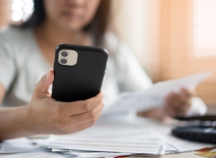 Worried woman looking at phone and paying bills stock photo