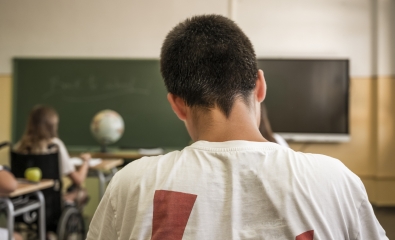 Teen boy in class with head down working