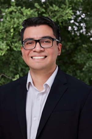 Headshot of Juan Venancio, in front of a tree/greenery background