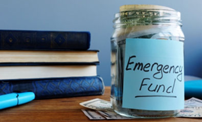 books on table with jar labeled emergency funds with money inside