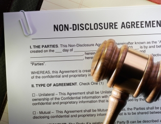 Non-disclosure agreement papers with a gavel sitting on top of the papers