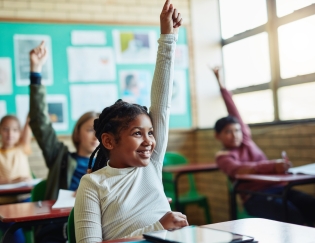 Happy girl raises hand in class, other students in background