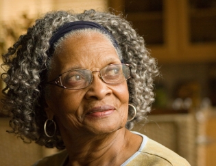Senior citizen Black woman in glasses smiling and looking up