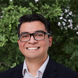 Headshot of Juan Venancio, in front of a tree/greenery background